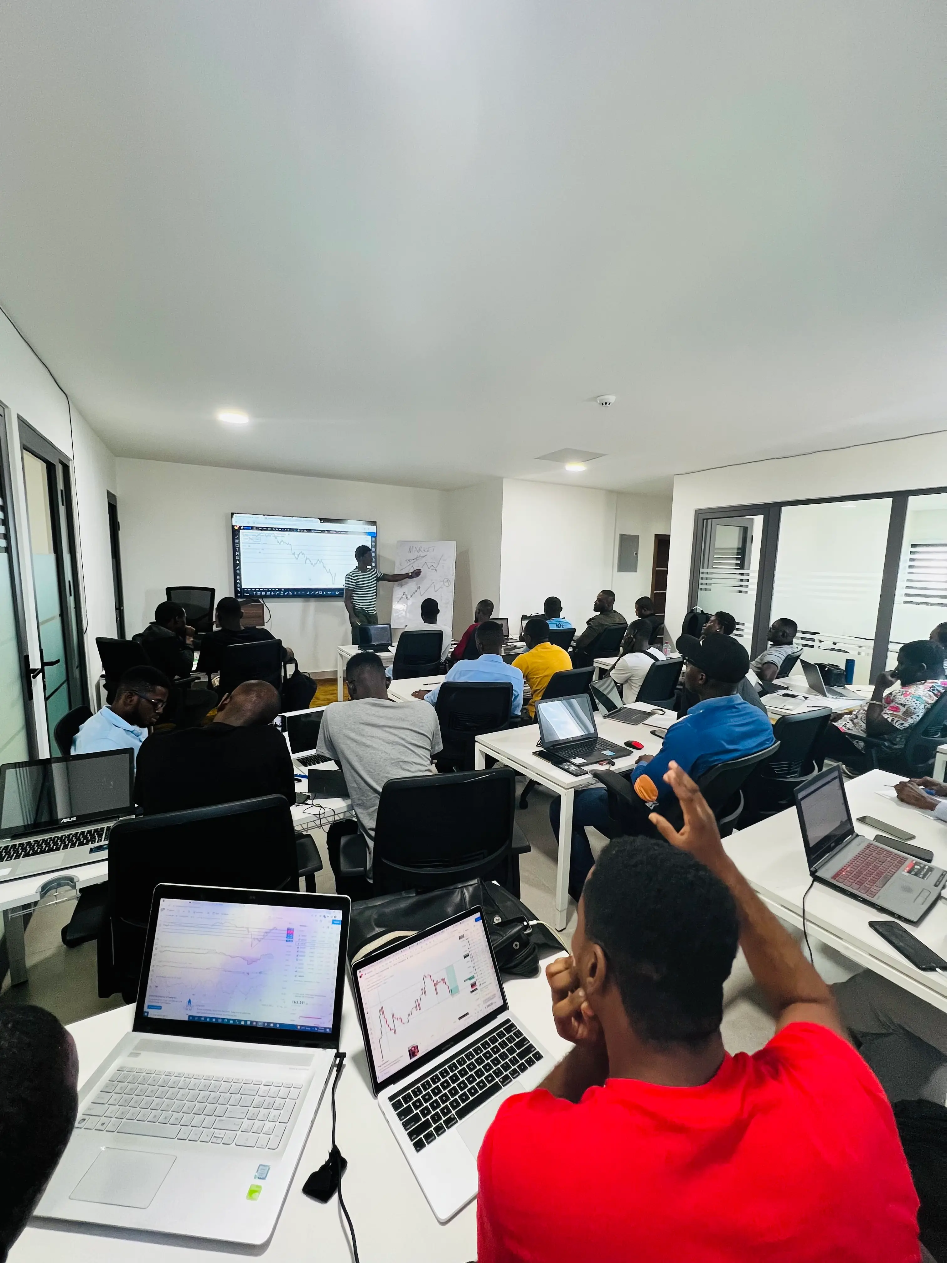 KojoForex Academy Physical Campus in Accra Ghana showing trading desks, ultra-wide monitors, and students analyzing live forex charts